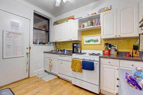 A kitchen with white cabinets and a white stove top oven.
