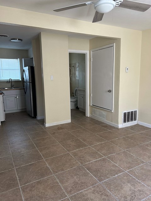 A room with a fan and tile flooring.