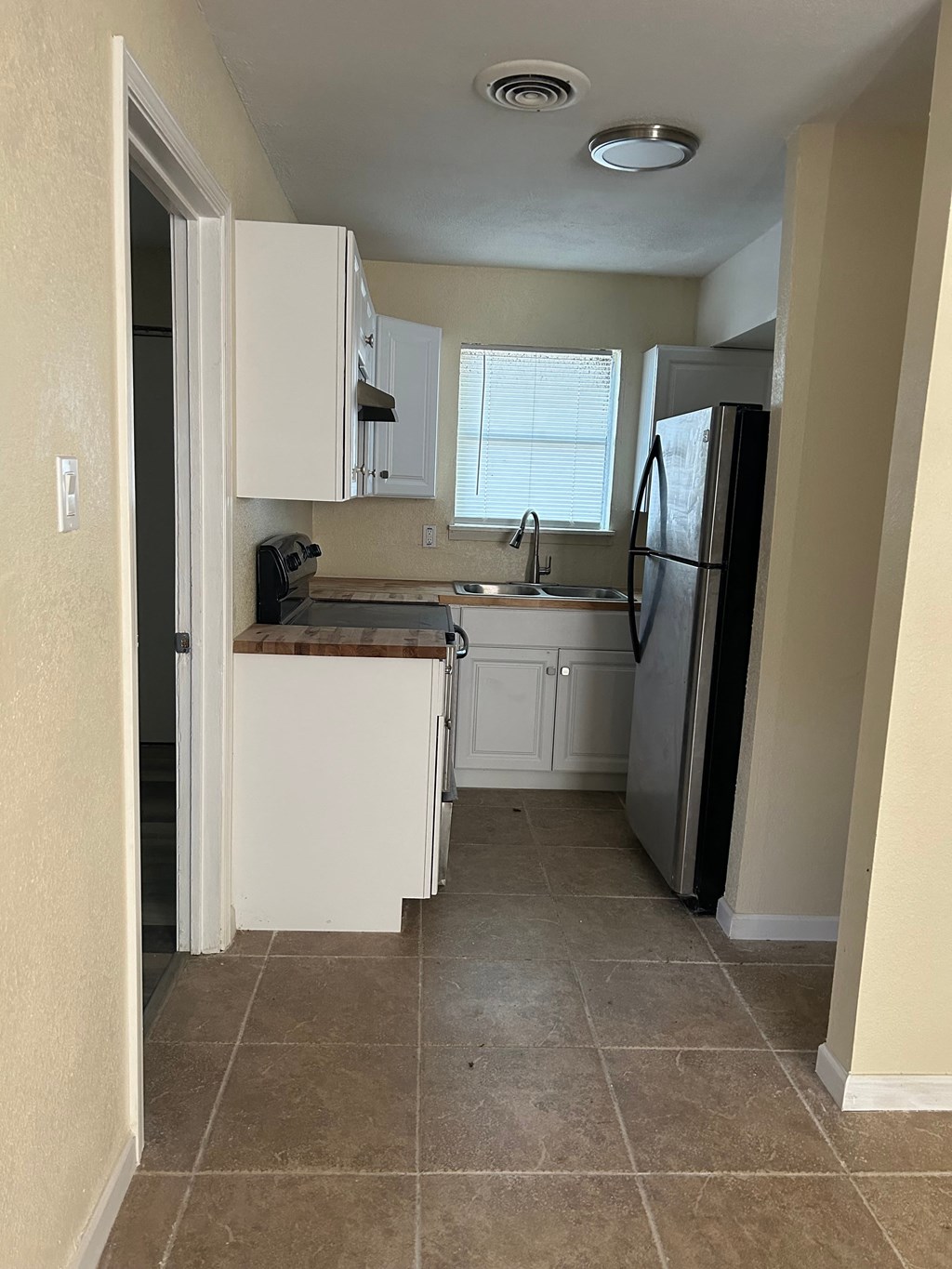 a small kitchen with white cabinets and a refrigerator