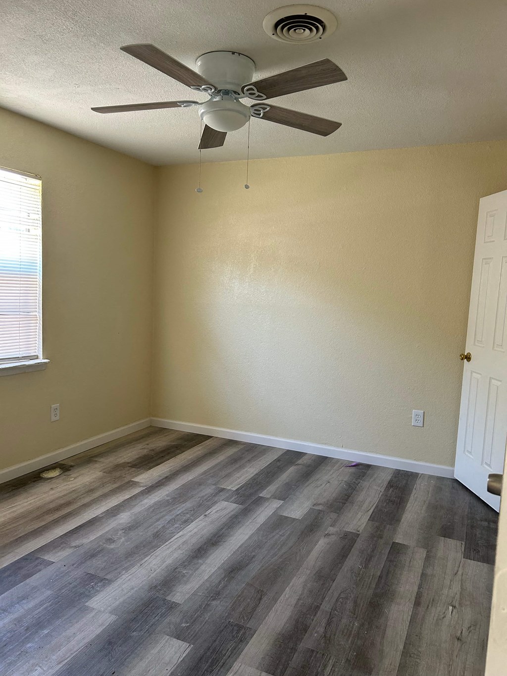 an empty living room with wood floors and a ceiling fan