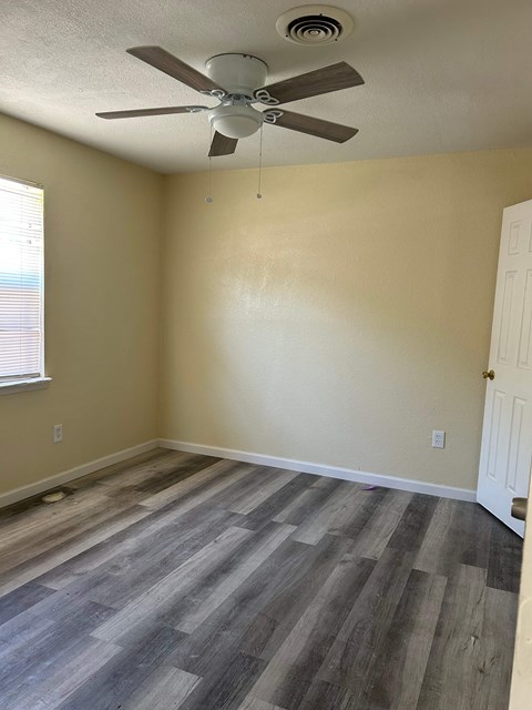 A room with a ceiling fan and wooden flooring.