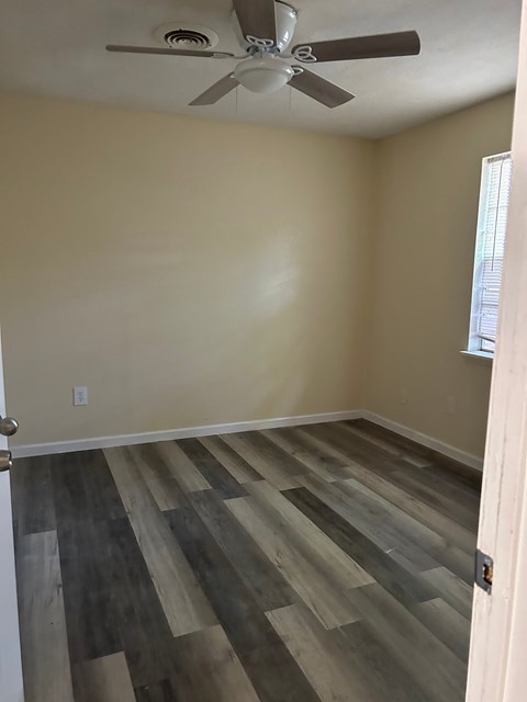 A room with a ceiling fan and wooden flooring.