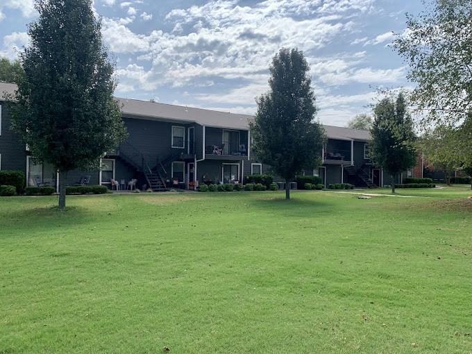 A grassy field in front of apartment buildings.