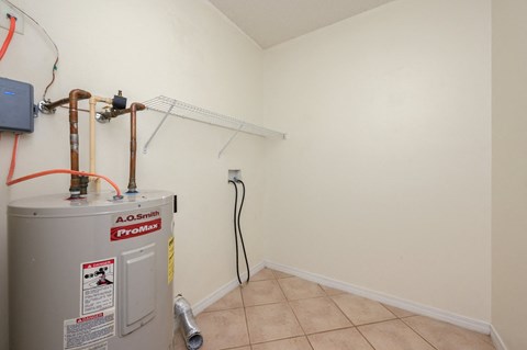 a room with a water heater and a radiator in the corner of it