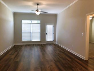 an empty living room with wooden floors and a ceiling fan