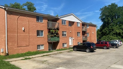 A black car is parked in front of a brick building.