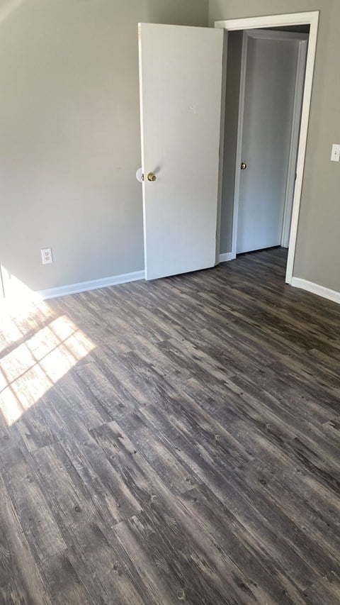 A room with a wooden floor and two white doors.