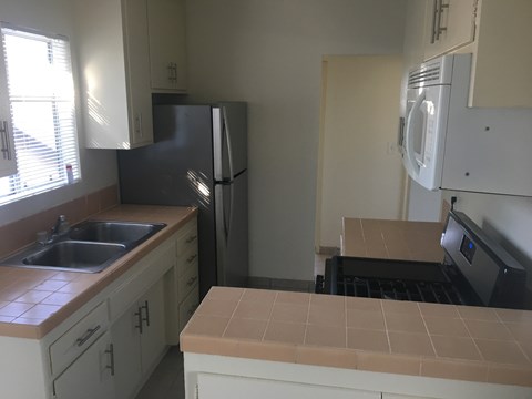 A kitchen with a black refrigerator and white cabinets.