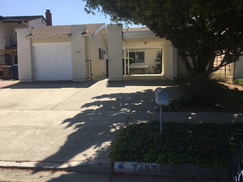 A house with a white garage door and a mailbox with the number 7487 on it.