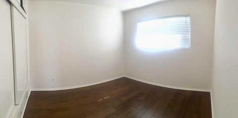 A room with a window and wooden flooring.