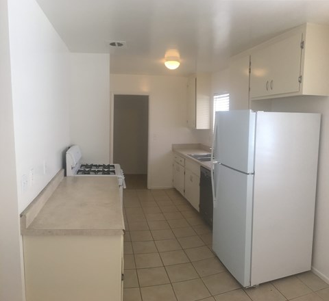 A kitchen with a white refrigerator and a white counter.
