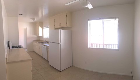 A white kitchen with a refrigerator, sink, and stove.