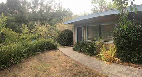 A house with a grey roof and a small garden in front.