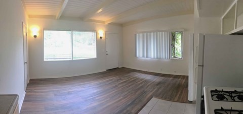 A room with a wooden floor and a window with blinds.