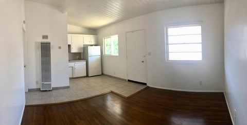 A large empty room with a wooden floor and white walls.