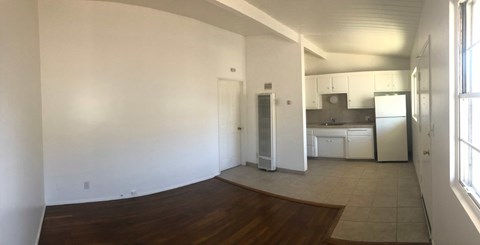 A kitchen area with white appliances and a wooden floor.