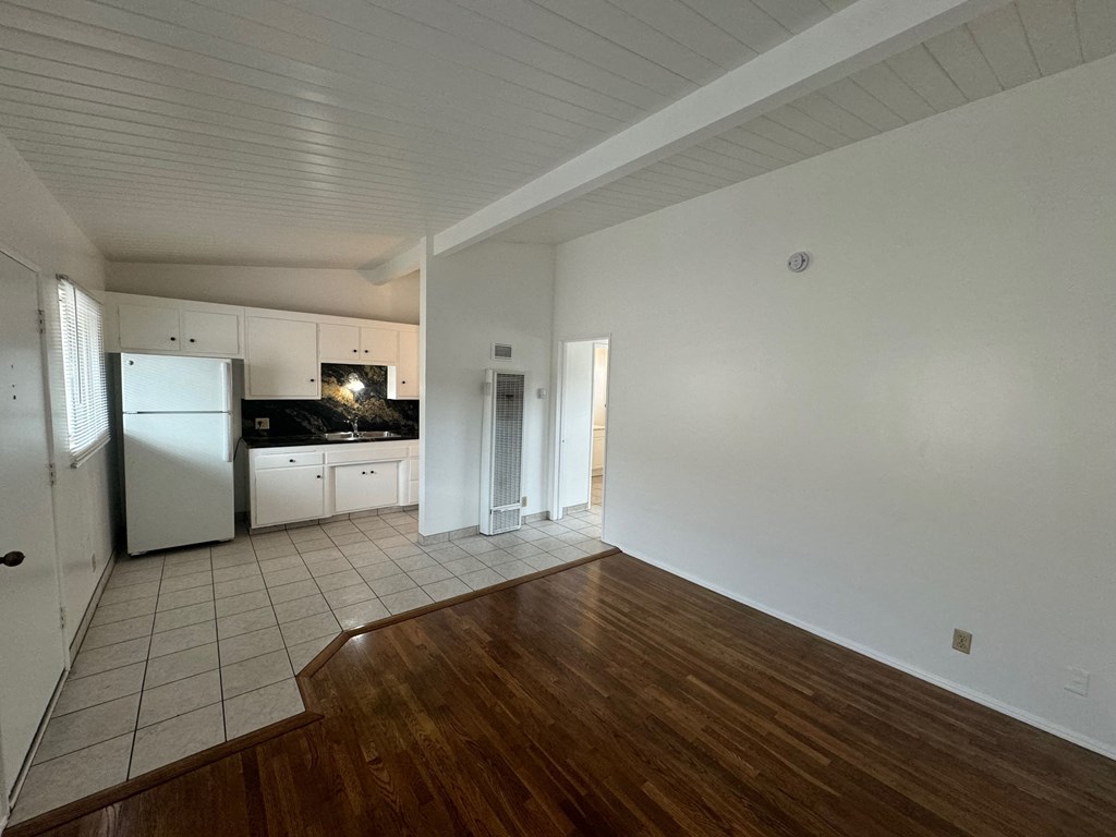 A kitchen with white cabinets and a refrigerator.