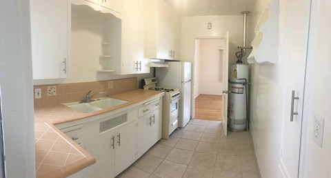 A kitchen with white cabinets and a tiled floor.