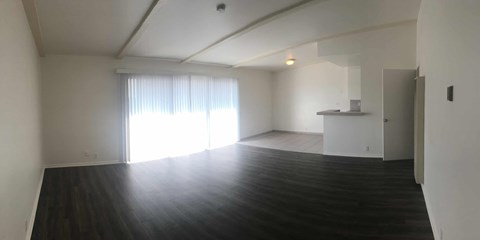 A large empty room with wooden floors and white walls.