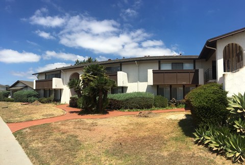 A white building with a red walkway in front.