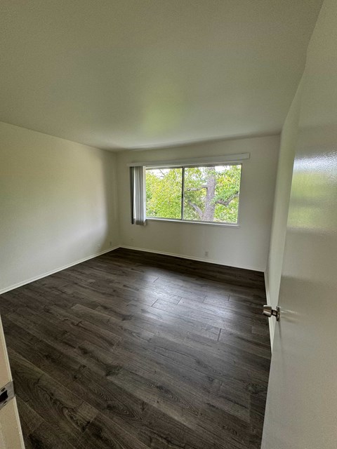 A room with a window and wooden flooring.