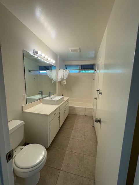 A white bathroom with a toilet, sink, and mirror.