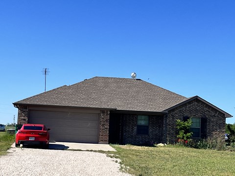 A red car is parked in front of a house.