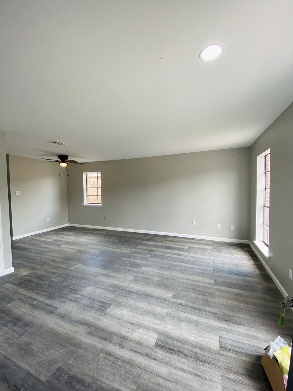 an empty living room with gray walls and a wooden floor
