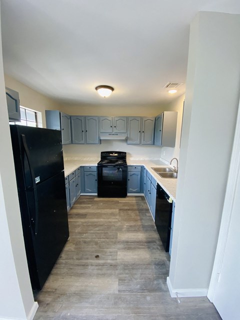 an empty kitchen with black appliances and blue cabinets