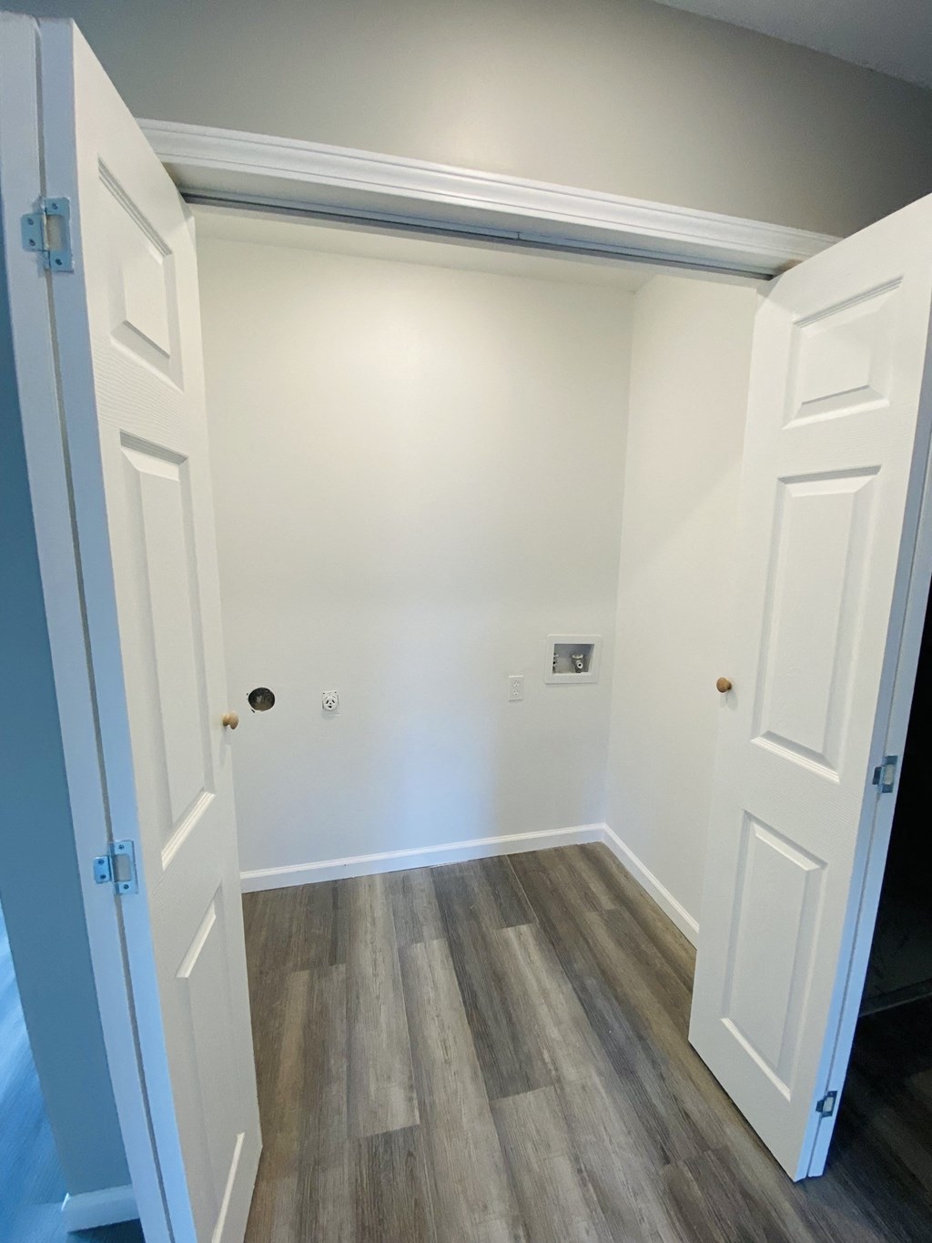 an empty hallway with white doors and wood flooring