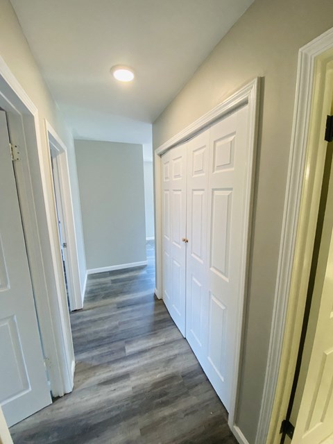 the hallway of a home with white closets and wood floors
