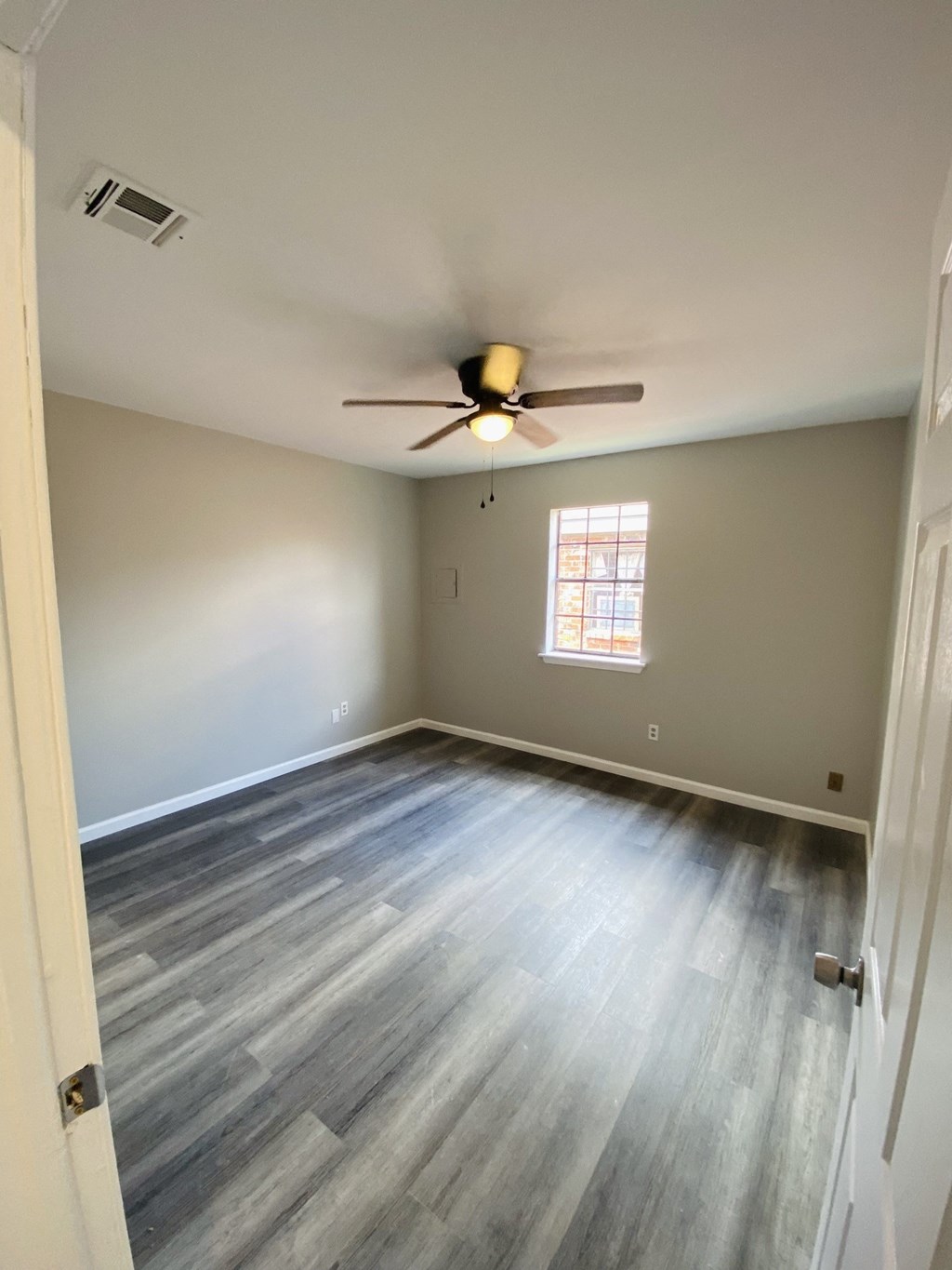 an empty living room with wood floors and a ceiling fan