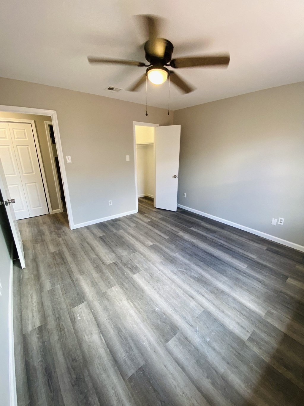 an empty living room with vinyl flooring and a ceiling fan