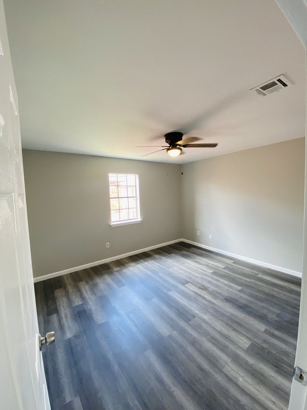 an empty living room with wood floors and a ceiling fan
