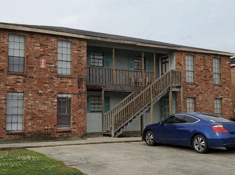 a blue car parked in front of a brick building