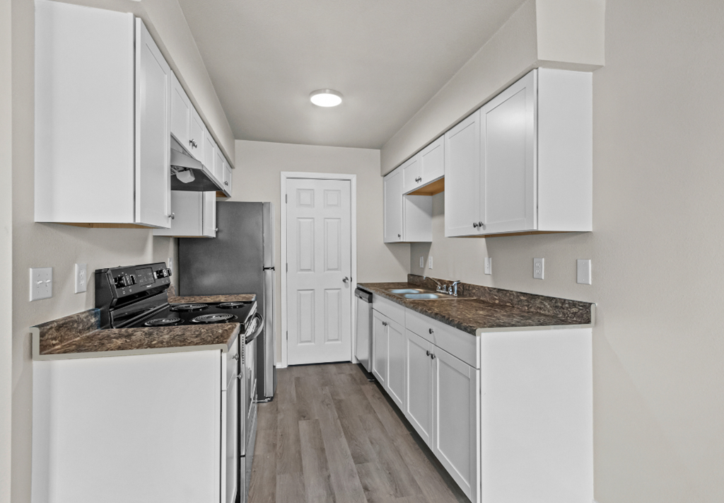 an empty kitchen with white cabinets and a white door