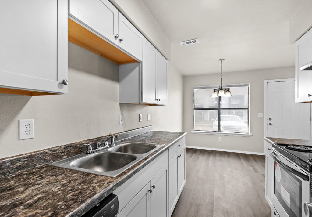 the kitchen of a home with white cabinets and granite counter tops