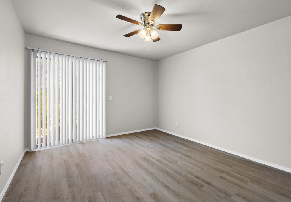 an empty living room with wood flooring and a ceiling fan