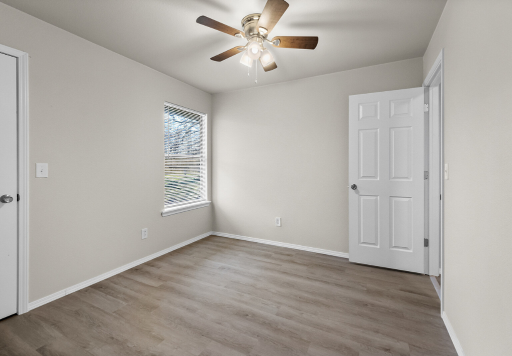 an empty bedroom with a ceiling fan and a door
