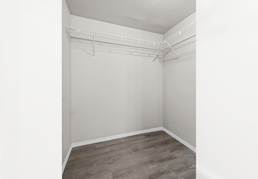 an empty room with white walls and wood flooring and a white closet with a