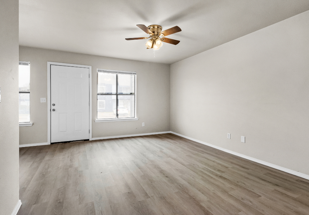 an empty living room with white walls and a ceiling fan
