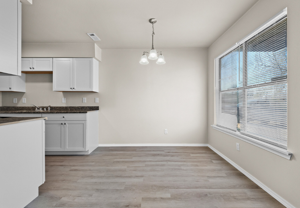 an empty kitchen with white cabinets and a large window