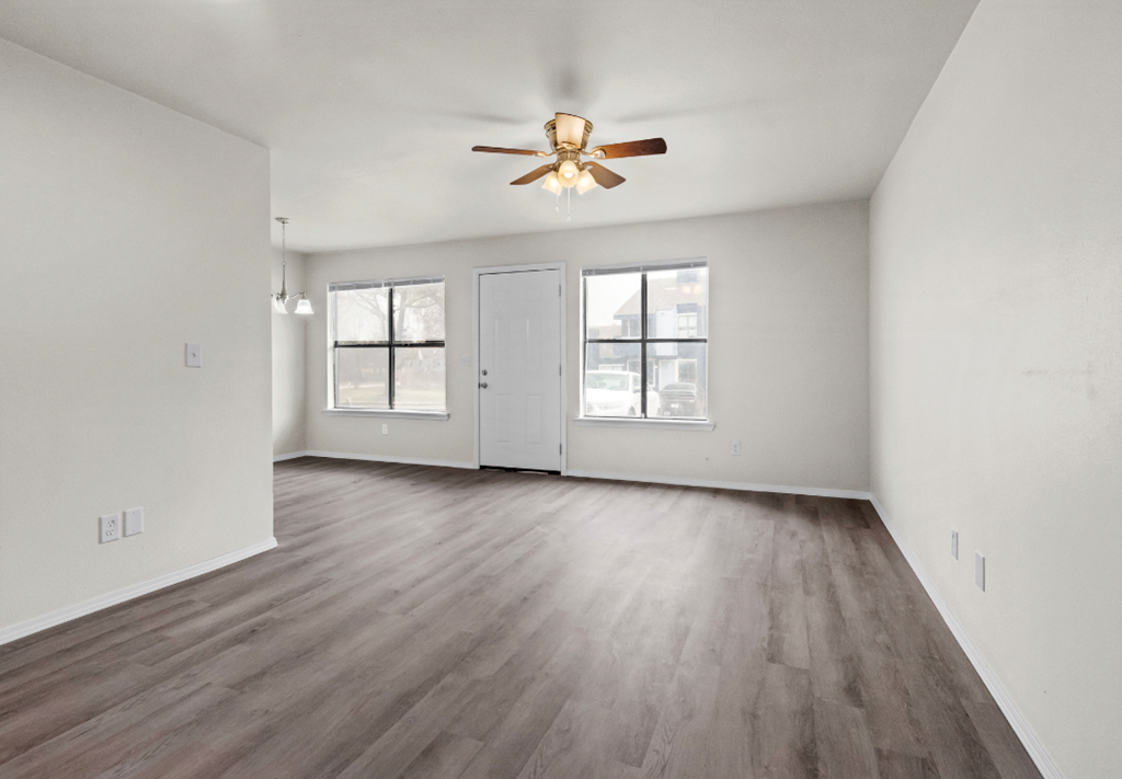 an empty living room with white walls and a ceiling fan