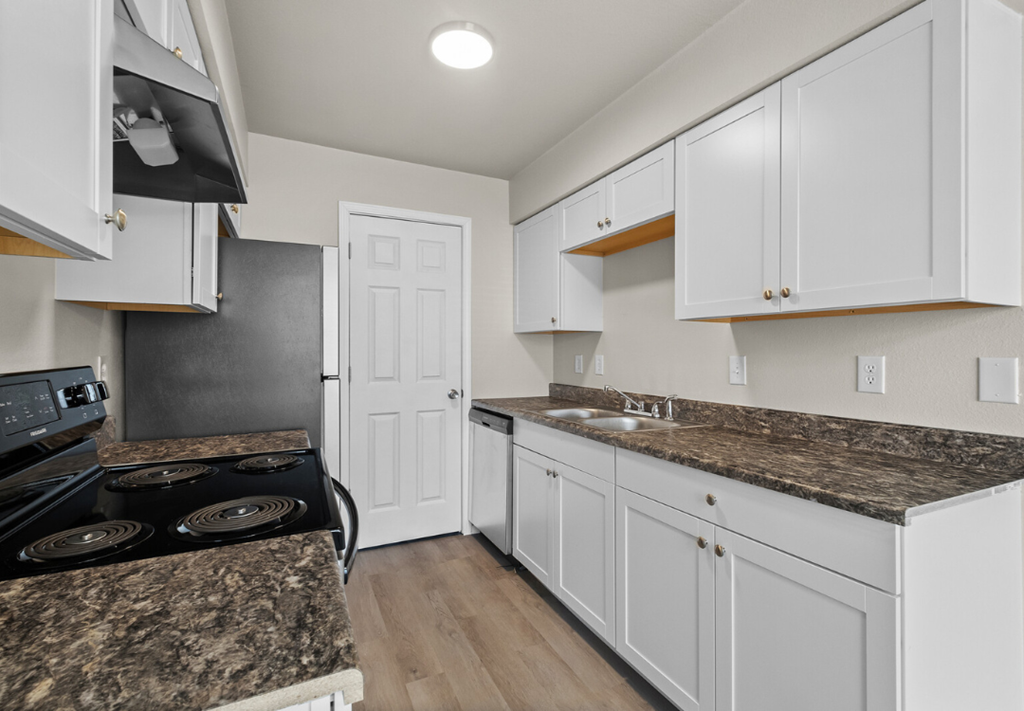 a kitchen with white cabinets and granite counter tops and a black stove