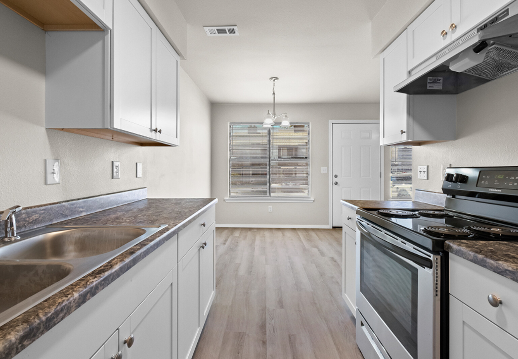 an empty kitchen with white cabinets and stainless steel appliances