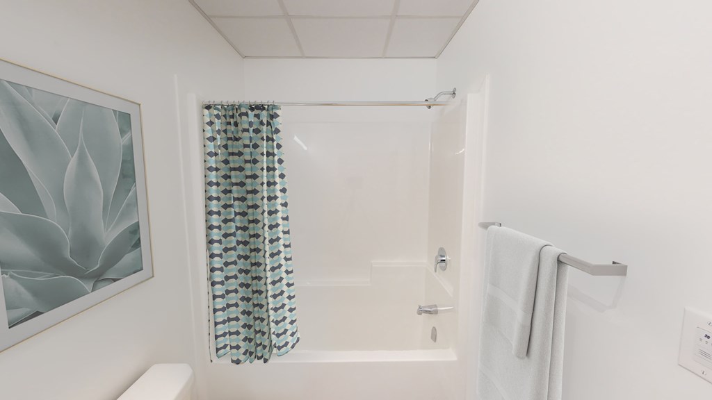 A white bathroom with a white toilet, a white bathtub, a white shower curtain, and a white towel.