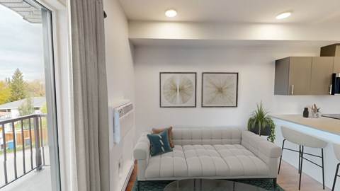 A living room with a white couch and a small kitchen area.