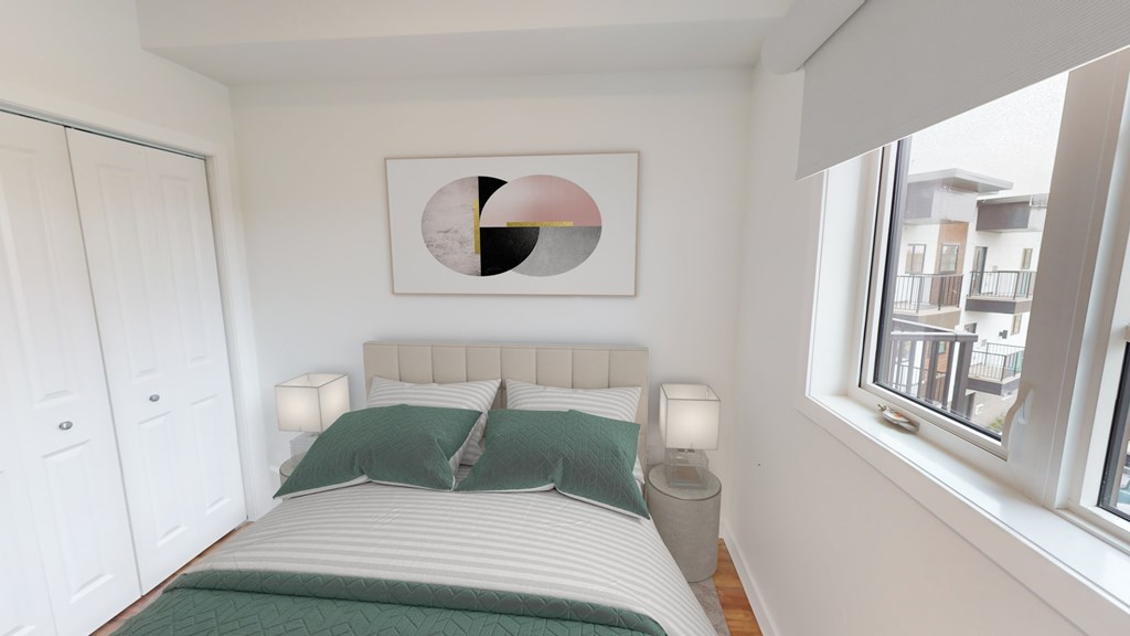 A bedroom with a bed, two pillows, a nightstand, and a framed picture on the wall.