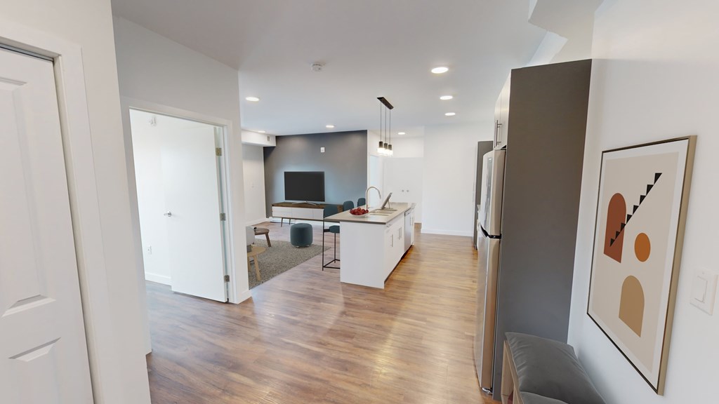 A modern kitchen with white appliances and a wooden floor.