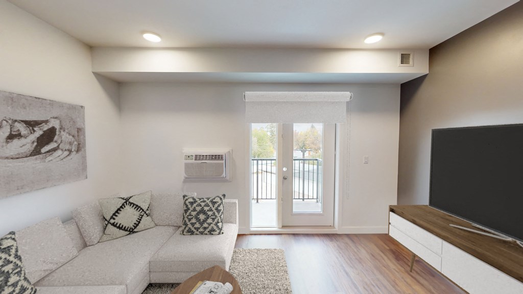 a living room with a couch and a tv and a door to a balcony
